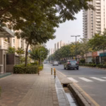 Shaded Gurugram residential street with towers, retail and pedestrian access